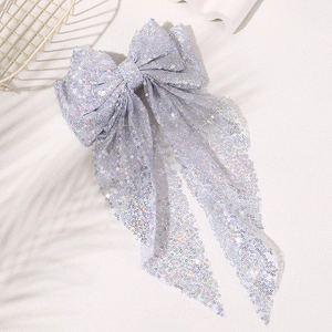 Macro shot of oversized silver sequin bow hair clip with shimmering metallic streamers