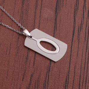 Détail du collier à pendentif rectangulaire en acier inoxydable argenté sur bois sombre