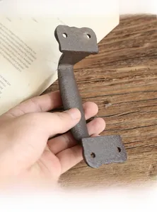 Detail of vintage cast iron drawer handle in dark bronze held by hand for size