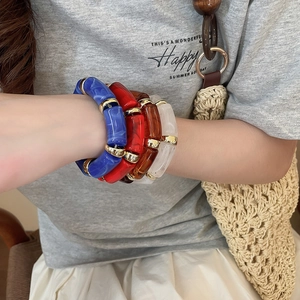 Detail of stacked acetate bangles with marble texture and gold spacers on a wrist