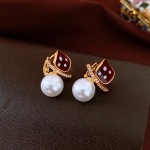 Detail of gold square earrings with red enamel polka dots and round pearl drops