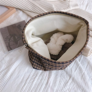 Internal view of a large plaid houndstooth cosmetic bag with zipper and cream lining