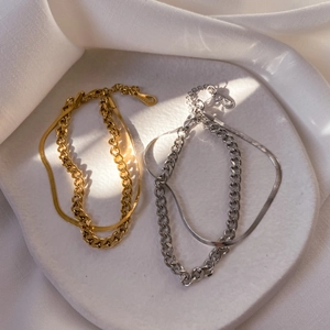 Dual-layer Cuban and snake chain bracelet set in gold and silver finish on ceramic plate