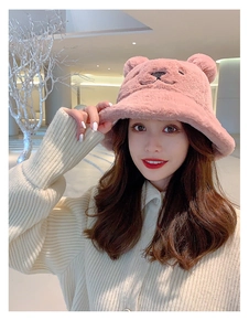 Detail of pink plush bucket hat with bear ears and embroidered face on model