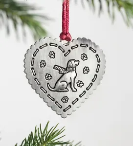 Macro shot of heart-shaped metal dog ornament with red silk ribbon on pine branches