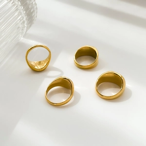 Close-up of four polished gold signet rings with smooth round faces on a minimalist base