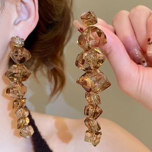 Macro detail of irregular amber acrylic block earrings showing light refraction