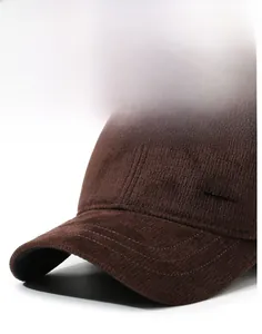 Detail of dark brown corduroy baseball cap with metal Fashion label and reinforced brim