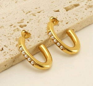Detailed macro view of U-shaped gold plated stainless steel earrings with pearl inlay