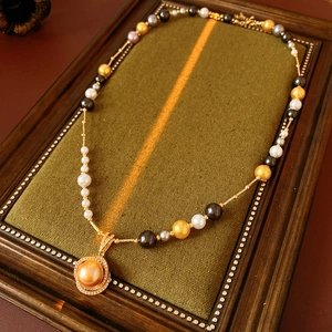 Macro detail of multicolor pearl necklace with gold pendant on green velvet base
