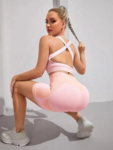 Pink seamless yoga set with cross-strap bra and high-waisted shorts showing mesh detail
