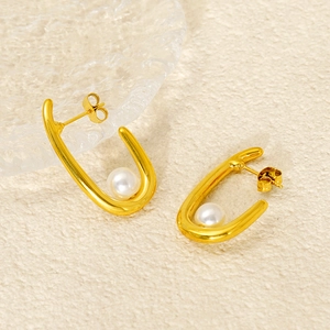 Élégantes boucles d'oreilles en forme de U dorées avec perles blanches sur fond sobre