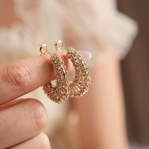 Macro shot of gold C-shaped earrings encrusted with sparkling rhinestones and clear backing
