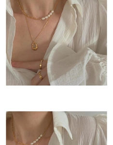 Detailed view of the layered gold pearl chain necklace and sleek minimalist rings