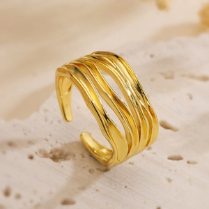 Detail of gold multilayer wavy ring on natural stone showing modern metallic textures