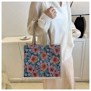Detailed side view of floral woven tote bag with beige rope handles on a white background