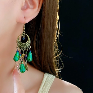 Detail of vintage bronze flower earrings with green waterdrop beads and leaf pendants