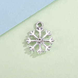 Sparkling silver snowflake pendant with center rhinestone on a minimalist background