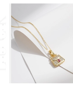 Macro detail of golden handbag pendant necklace with red pear-cut gem and zircon stones
