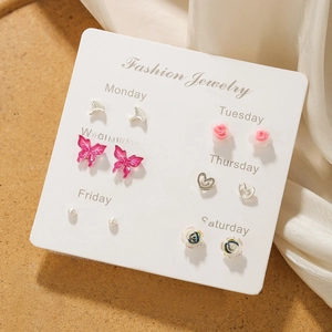 Close-up of 6 pairs butterfly and rose stud earring set displayed on a weekday card