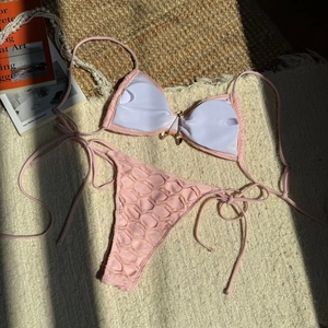 Detail of pink honeycomb texture bikini top with a golden butterfly charm and tie strings