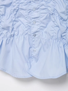 Détail d'une chemise en popeline bleu clair avec smocks plissés et petits boutons assortis