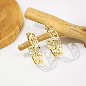 Golden C-shaped hoop earrings with hollow star patterns on a wooden display stand