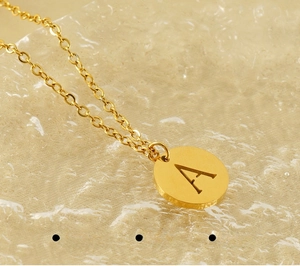 Macro detail of polished gold 18K plated stainless steel pendant with engraved letter A