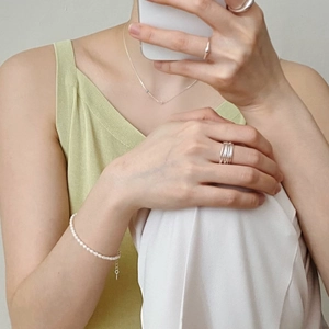 Close-up of 925 sterling silver multi-layered ring and pearl bracelet on model