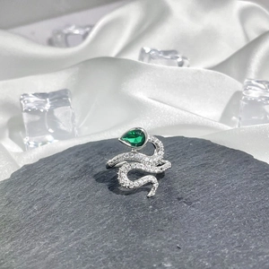 Macro shot of silver snake ring featuring green pear-cut stone and white pavé crystals