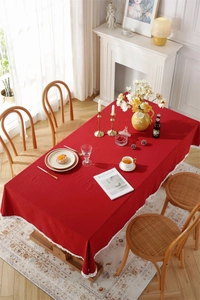 Detail of red cotton tablecloth featuring delicate white lace trim on a dining table