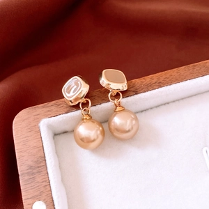 Dettaglio di orecchini dorati vintage con eleganti perle champagne pendenti