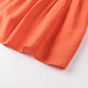 Gros plan de l'ourlet en tissu orange texturé avec coutures détaillées sur le pantalon