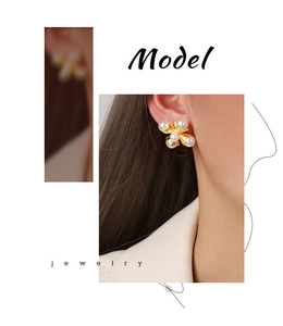 Close-up of gold-plated cross earrings featuring elegant white pearls on a female model