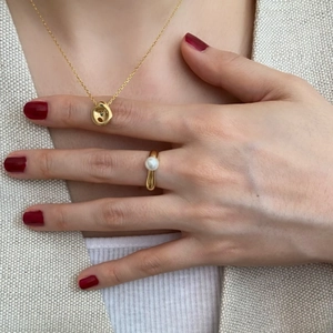 Detail of a minimalist gold irregular pendant necklace and a sleek white pearl ring set