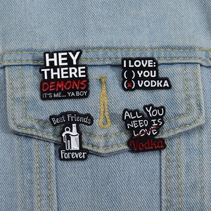 Detail of four creative enamel pins with humorous vodka slogans on denim jacket