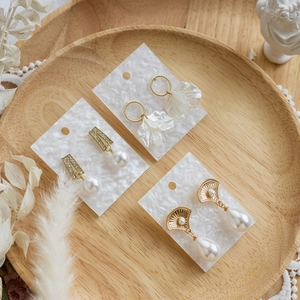 Elegant gold pearl earrings set displayed on white cards within a rustic wooden tray