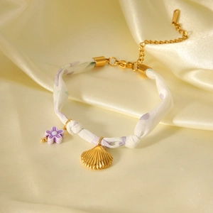 Elegant gold seashell and purple resin flower scarf bracelet on soft silk background