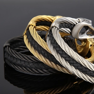 Close-up of three braided steel wire and leather men's bracelets in gold, silver, and black
