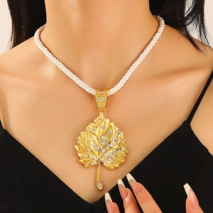 Detail of gold maple leaf pendant with sparkling rhinestones on a white twisted rope chain