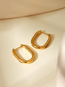 Macro view of polished gold-plated U-shaped hoop earrings with a mirror finish