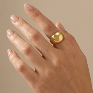 Close-up of a chunky golden polished stainless steel ring worn on a finger