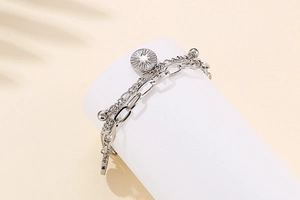 Detail of silver layered chain bracelet with sunburst star pendants on white display