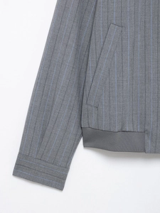 Detail of grey varsity jacket with blue pinstripes showing ribbed cuffs and side pockets