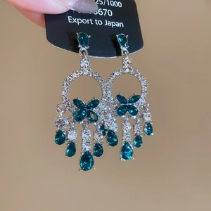 Close-up of S925 silver earrings featuring green teardrop gems and zircon butterfly fringe