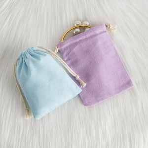 Detail of light blue and purple cotton linen drawstring pouches on white faux fur background
