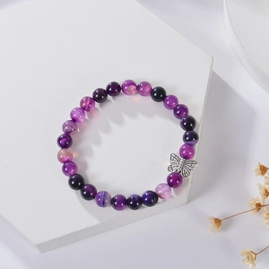 Detail of 8mm purple zebra stone bead bracelet with silver butterfly charm on white pedestal