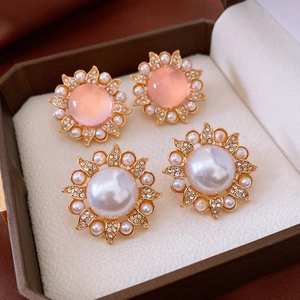 Détail de boucles d'oreilles vintage avec pierres roses, perles blanches et cristaux