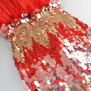 Close-up of red sequin party dress with fluffy feather trim and golden metallic details