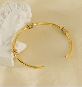Detail of 18K gold plated stainless steel open bangle with twisted chain accents